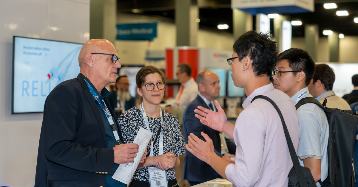 Photo of three attendees talking in the OTO EXPO exhibit hall.